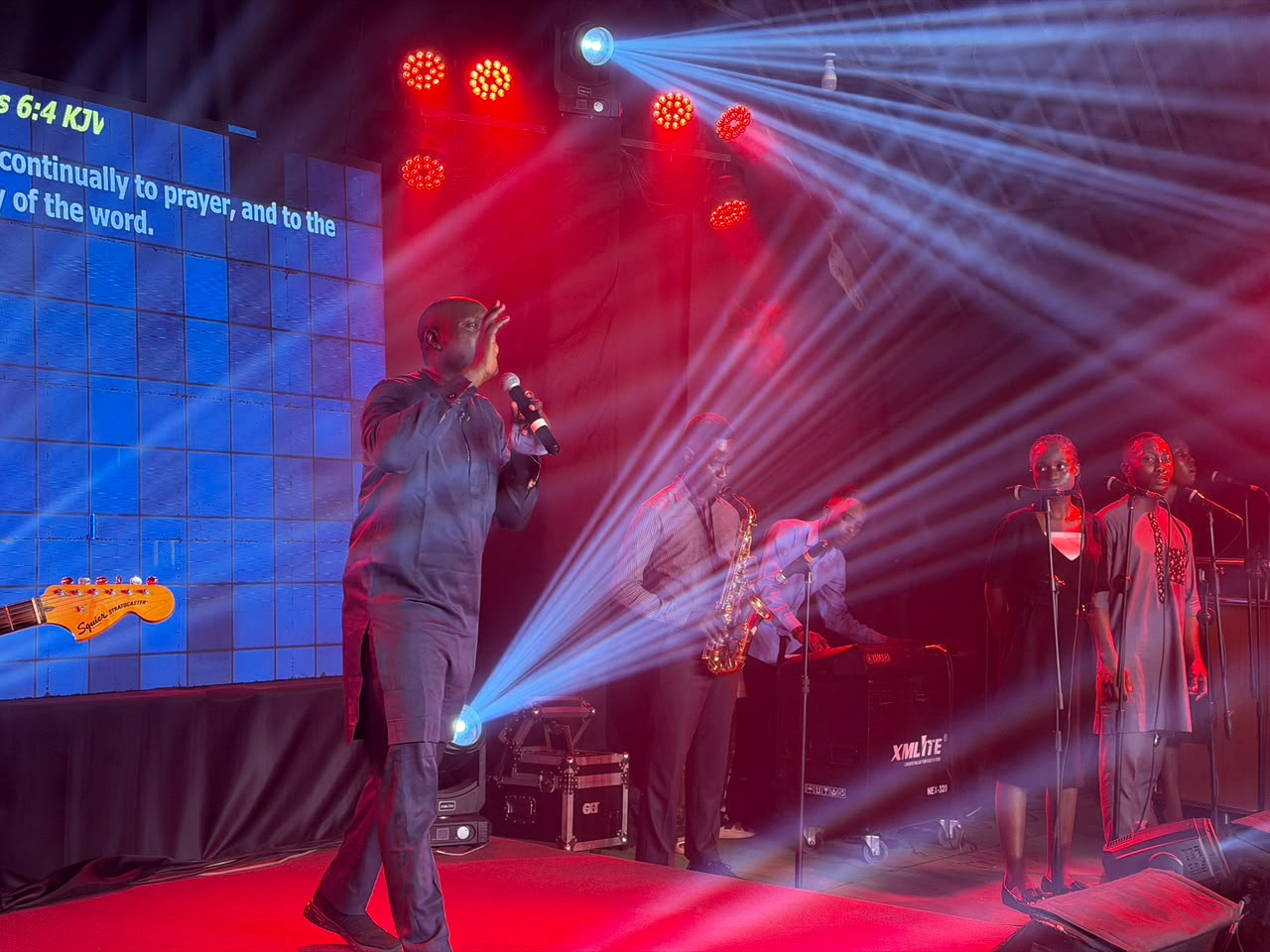 The AIGC worship team leading a service — vocalists, saxophonist, and worship leader on stage